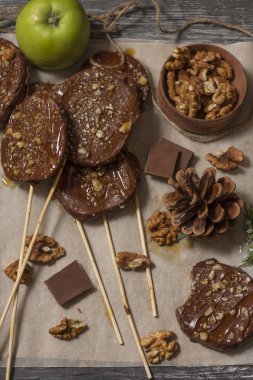 Koyu bir arka plan üzerinde şişler üzerinde çikolata, karamel sır ve ceviz elma dilimleri
