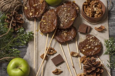 Koyu bir arka plan üzerinde şişler üzerinde çikolata, karamel sır ve ceviz elma dilimleri