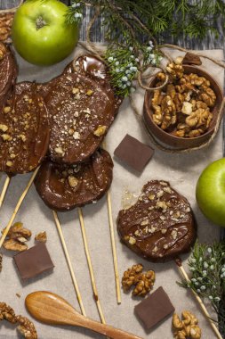 Koyu bir arka plan üzerinde şişler üzerinde çikolata, karamel sır ve ceviz elma dilimleri