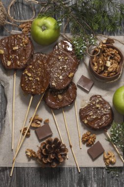 Koyu bir arka plan üzerinde şişler üzerinde çikolata, karamel sır ve ceviz elma dilimleri