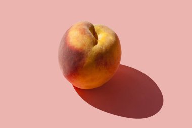 Sert bir gölge ile pastel pembe arka plan üzerinde sulu olgun şeftali