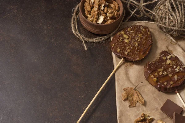 Koyu bir arka plan üzerinde şişler üzerinde çikolata, karamel sır ve ceviz elma dilimleri