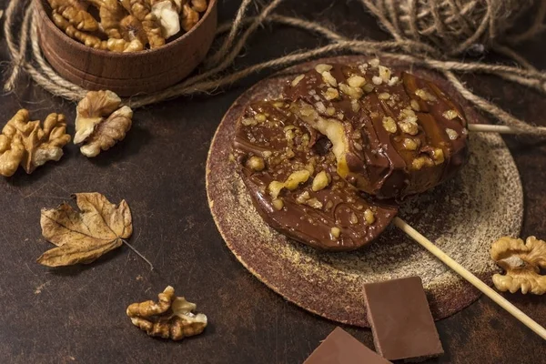Koyu bir arka plan üzerinde şişler üzerinde çikolata, karamel sır ve ceviz elma dilimleri