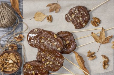 Koyu bir arka plan üzerinde şişler üzerinde çikolata, karamel sır ve ceviz elma dilimleri