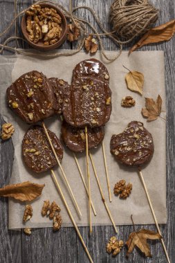 Koyu bir arka plan üzerinde şişler üzerinde çikolata, karamel sır ve ceviz elma dilimleri