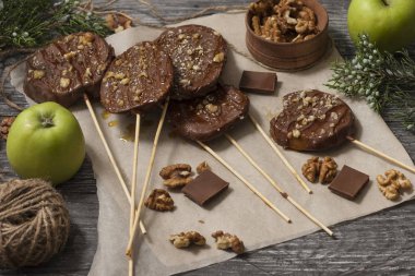 Koyu bir arka plan üzerinde şişler üzerinde çikolata, karamel sır ve ceviz elma dilimleri