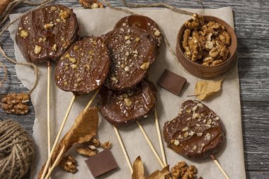 Koyu bir arka plan üzerinde şişler üzerinde çikolata, karamel sır ve ceviz elma dilimleri