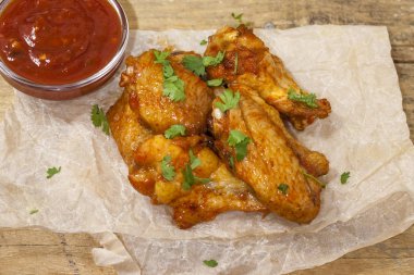 Kızarmış sulu tavuk kanatları bal, soya sosu, baharat, ince doğranmış kişniş ile bir kağıt arka plan serpilir marine. Asya tarifi, üstte, yakın çekim.