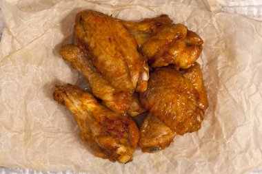 Kızarmış sulu tavuk kanatları bal, soya sosu ve baharatlar bir kağıt arka plan üzerinde marine. Asya tarifi, üstte, yakın çekim.