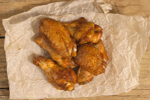 Fried juicy chicken wings marinated with honey, soy sauce and spices on a paper background. Asian recipe, top view, close-up.