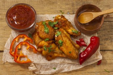 Kızarmış sulu tavuk kanatları bal, soya sosu, baharat, ince doğranmış kişniş ile bir kağıt arka plan serpilir marine. Asya tarifi, üstte, yakın çekim.