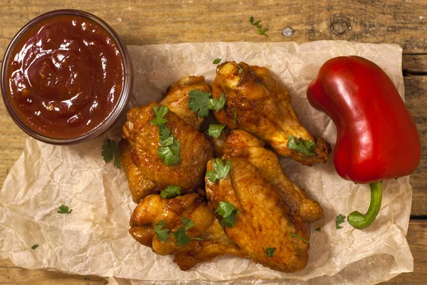 Ali di pollo fritte e succose marinate con miele, salsa di soia, spezie, cosparse di coriandolo tritato finemente su fondo di carta. Ricetta asiatica, vista dall'alto, primo piano . — Foto Stock