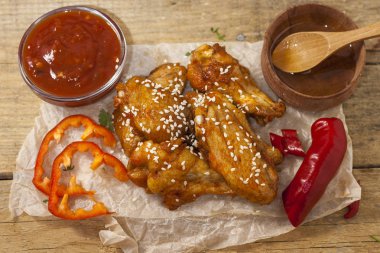 Kızarmış sulu tavuk kanatları bal, soya sosu, baharat, ince doğranmış kişniş ile bir kağıt arka plan serpilir marine. Asya tarifi, üstte, yakın çekim.