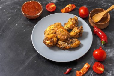 Kızarmış sulu tavuk kanatları bal, soya sosu, baharat, domates, kırmızı biber, bal ve biber sosu ile siyah bir arka plan üzerinde bir tabak üzerinde chia tohumu serpilir marine. Asya tarifi, üst tesbil.