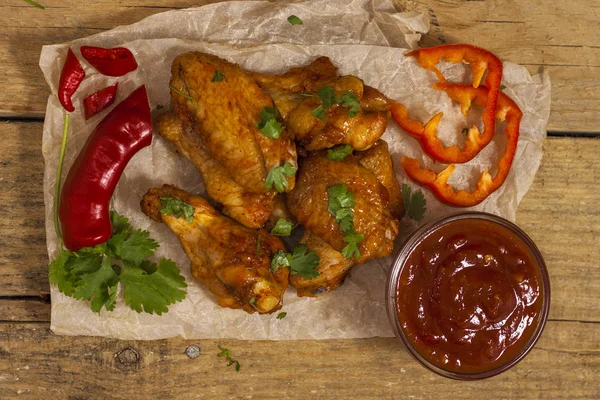 Fried juicy chicken wings marinated with honey, soy sauce, spices, sprinkled with finely chopped cilantro on a paper background. Asian recipe, top view, close-up. — Stock Photo, Image