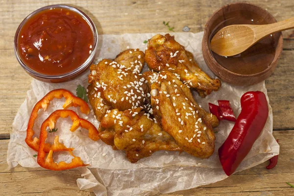 Kızarmış sulu tavuk kanatları bal, soya sosu, baharat, ince doğranmış kişniş ile bir kağıt arka plan serpilir marine. Asya tarifi, üstte, yakın çekim.