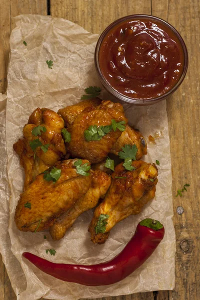 Ali di pollo fritte e succose marinate con miele, salsa di soia, spezie, cosparse di coriandolo tritato finemente su fondo di carta. Ricetta asiatica, vista dall'alto, primo piano . — Foto Stock