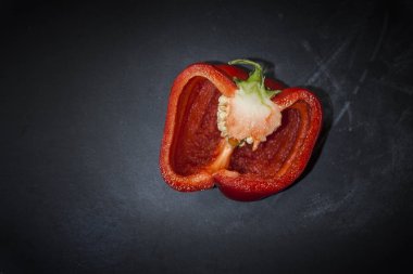 Yarım siyah bir arka plan üzerinde taze olgun kırmızı biber kesilmiş