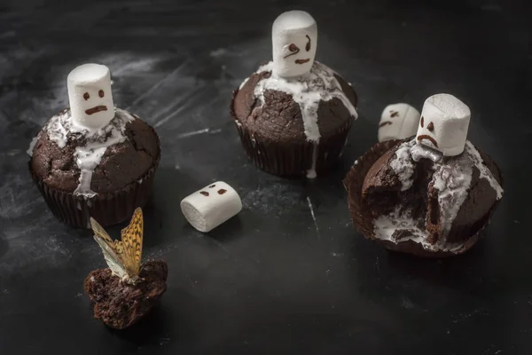 Ein köstliches Dessert zu Halloween, Schokoladenmuffins mit süßen Geistern aus Marshmallows auf schwarzem Hintergrund. — Stockfoto