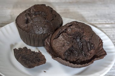 Hafif bir arka plan c beyaz bir tabak üzerinde ısırır çikolatalı muffin