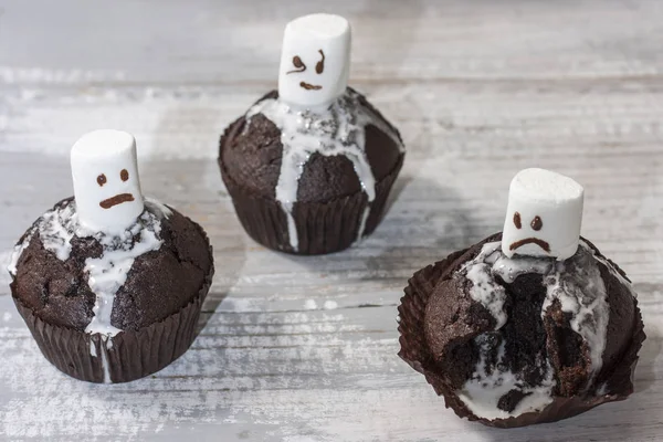 Un delicioso regalo para el postre de Halloween, magdalenas de chocolate con fantasmas dulces de malvaviscos sobre un fondo blanco . — Foto de Stock