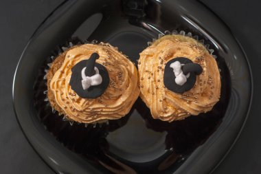 Mutlu Halloween turuncu ve siyah bir tabak üzerinde boncuk ile siyah cadı şapka ve tereyağı krem ile siyah dekore cupcake.