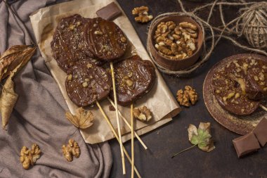 Koyu bir arka plan üzerinde şişler üzerinde çikolata, karamel sır ve ceviz elma dilimleri