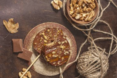 Çikolata elma dilimleri, karamel sır ve koyu bir arka plan üzerinde şiş ler üzerinde ceviz. Kopyalama alanı.