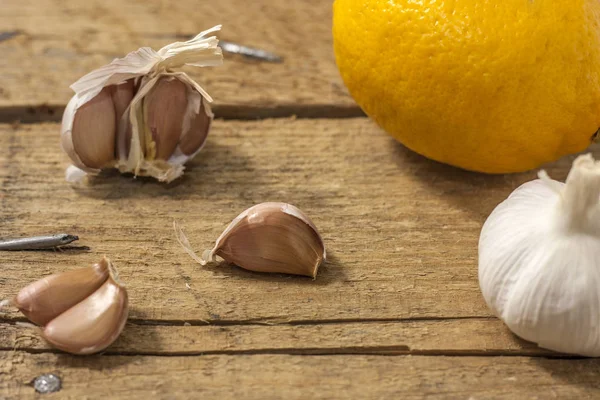 Garlic clove and lemon on a wooden background. The concept of the treatment of colds with folk remedies — Stock Photo, Image