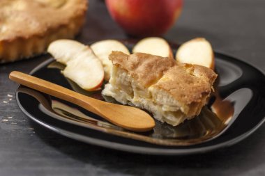 Elmalı turtayı siyah bir tabakta siyah tahta bir kaşıkla dilimle. Yaklaş..