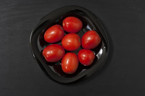 Gefermenteerd voedsel op een zwarte plaat op een zwarte houten tafel. Gekneusde tomaten en komkommers. Zout voor de winter. Traditionele snack voor alcohol. — Stockfoto