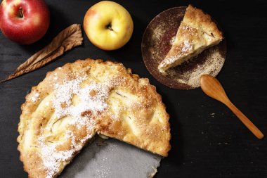 Elmalı turta Charlotte siyah ahşap bir masada, kırmızı elmalar demir şeklinde..