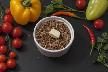 Karabuğday lapası, siyah ahşap bir arka planda, sebzeli, derin bir tabakta..