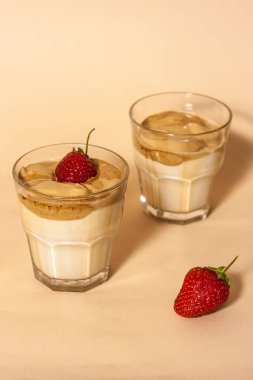 Şeffaf bardakta Dalgon kahvesi ve pastel arka planda çilekli süt..