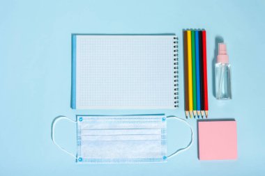 Okul kırtasiyesi ve tıbbi maskeler masanın üzerinde, mesafenizi koruyun, açık okulu, koronavirüs salgını için okula dönün, 19 'a kadar enfekte olduktan sonra..