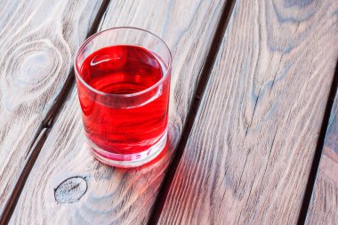 Ahşap bir masada kırmızı bir içki..