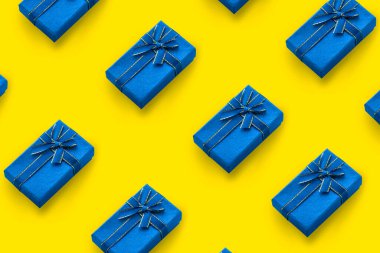 Sarı arka planda bir kurdeleyle bağlanmış mavi hediye kutularının deseni