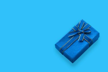 Açık mavi arkaplanda kurdeleyle bağlanmış mavi hediye kutusu ve kopyalama alanı.