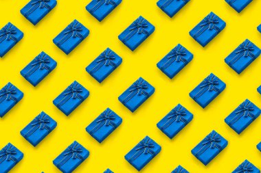 Sarı arka planda bir kurdeleyle bağlanmış mavi hediye kutularının deseni