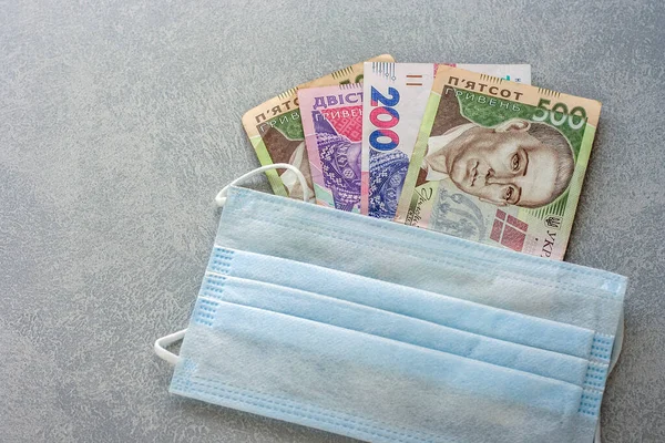 Koruyucu tıbbi maske Ukrayna para birimi Hryvnia 'ya dayanır. Coronavirüs döneminde alışveriş kavramı.