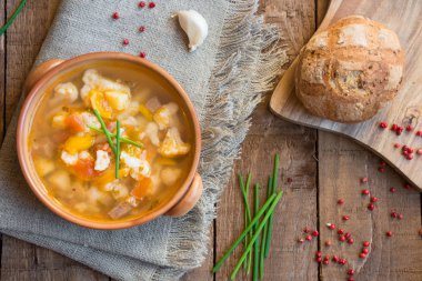 Ahşap masa üzerinde ekmek ve yeşil soğan ile sebze çorbası