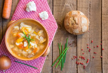 Ahşap masa üzerinde ekmek ve yeşil soğan ile sebze çorbası