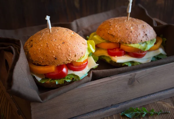 Deliciosos sándwiches con queso, lechuga, verduras y arugola sobre fondo oscuro — Foto de Stock