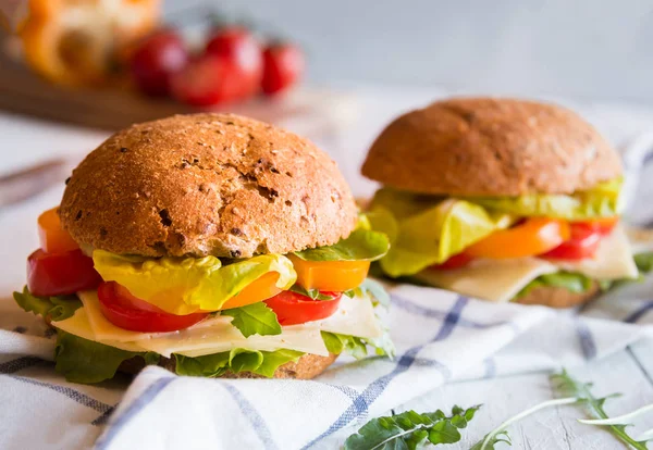 Leckere Sandwiches mit Käse, Salat, Gemüse und Rucola auf weißem Hintergrund — Stockfoto