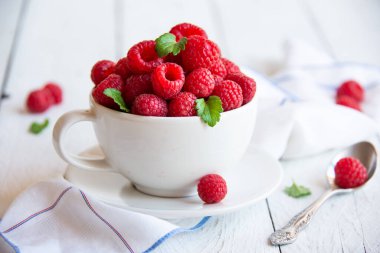 Beyaz fincanda yapraklı olgun ahududu.