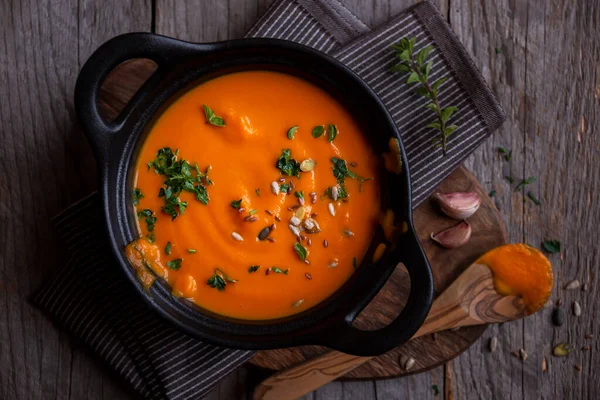 Hot pumpkin soup in cooking pot on dark wood