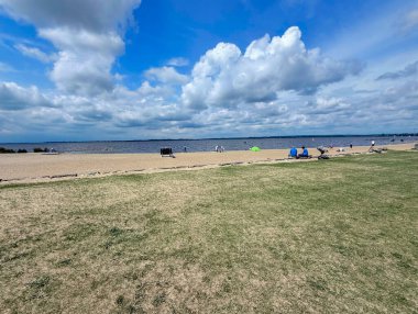 Bulutlu gökyüzünün altında sakin göl suyunda eski iskele ve sazlıklar.