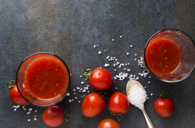 Karanlık mutfak masasında domates suyu, taze domates ve tuz üstten görünüm