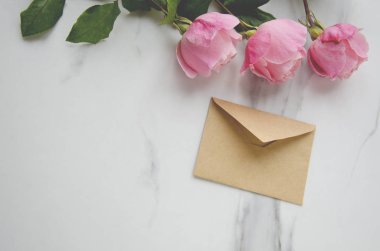 Pembe güller ve mermer masa zanaat zarfta. Tebrik kavramı