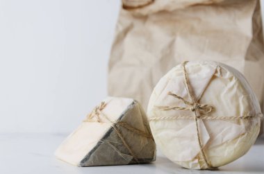 Eko paket beyaz masa üzerinde karşı gazetede lezzetli gouda, camembert Paketli